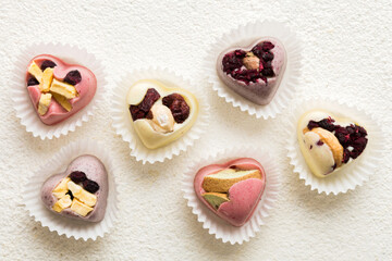 chocolate sweets in the form of a heart with fruits and nuts on a colored background. top view with space for text, holiday concept