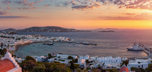 Panoramic summer evening view of the town of Mykonos island with the old port, famous windmills and...