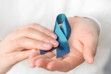 Holding blue ribbon for cancer awareness month. Healthcare and world cancer day concept.