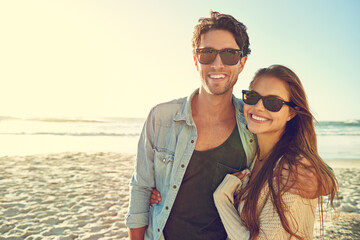 Couple, ocean and sunglasses with hug, happy or care for fashion, eye protection or vacation in summer. Man, woman and embrace in glasses at beach for sun, style or love by waves on tropical holiday