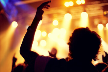 Night, club and man dance at concert, event or music festival with stage lights and silhouette. Dark, nightclub and person in audience, crowd and social celebration at techno rave with energy
