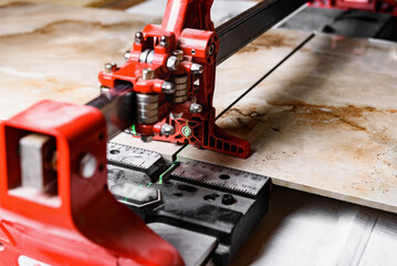 Close up of cutting ceramic tile with red manual tile cutter.