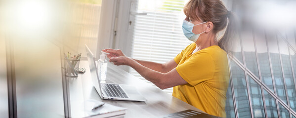 Businesswoman with medical face mask applying sanitizer on her hands; multiple exposure