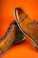 A pair of premium calfskin boots on an orange background. Vertical shot.