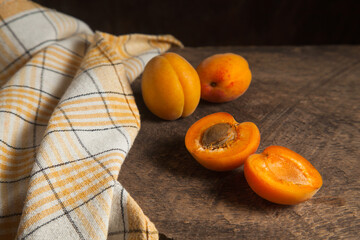 Apricot fruit whole and half on wooden background..