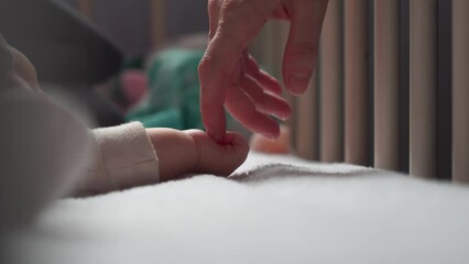 Mother gently and slowly touch sleeping newborn baby hand little fingers