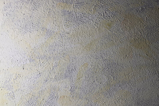 Parete con texture materica dipinta a tempera di colore grigio-giallo; spazio per testo