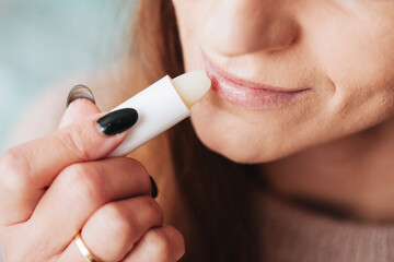 Woman using petrolatum on her mouth. Closeup lips background. Applying lip salve on lips with lipstick. Beauty background. Young girl skin care. Cosmetics for moisturize. Happy woman smile. - obrazy, fototapety, plakaty