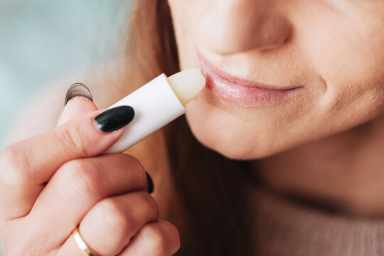 Woman using petrolatum on her mouth. Closeup lips background. Applying lip salve on lips with lipstick. Beauty background. Young girl skin care. Cosmetics for moisturize. Happy woman smile.