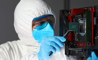 Man in uniform sets microchip electronic equipment. Hip testing microelectronics. Manual assembly...