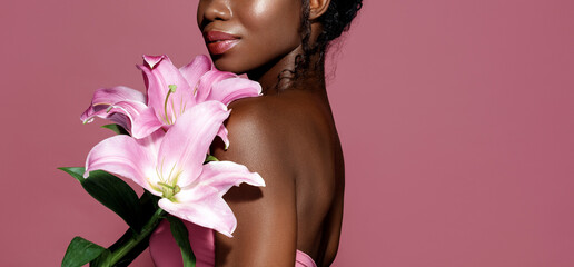 Beauty and Spa. Attractive African American young model holding  lily bouquet and posing against...