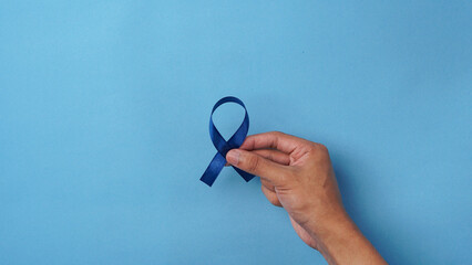 Hand holding blue ribbon on white background. supporting world concern day