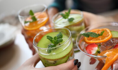 Hands holding glasses with cooling fruit cocktails. Learning cocktails online during quarantine. Bartenders competing over Internet during pandemic. Classic and popular cocktails world