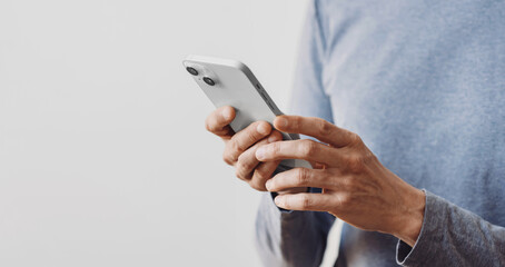 Closeup of adult male hand using mobile phone, Young man texting on smartphone over grey background