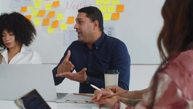Handheld shot of multiethnic colleagues listening to male product manager when talking about app launch