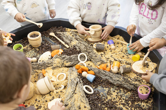 unrecognizable little children manipulating natural materials on a work table in kindergarten