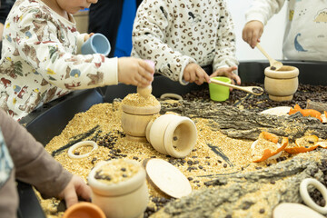 unrecognizable little children manipulating natural materials on a work table in kindergarten