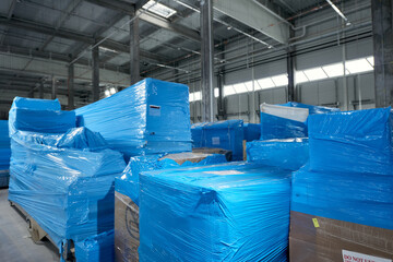 Products and boxes are stored in a warehouse, wrapped in blue stretch film - obrazy, fototapety, plakaty