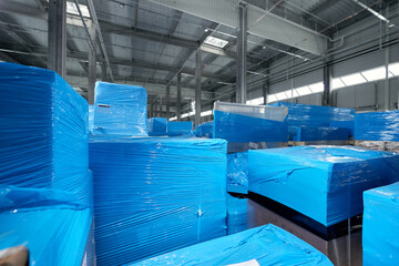 Products and boxes are stored in a warehouse, wrapped in blue stretch film