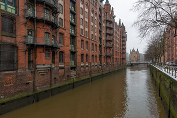 Naklejka premium Germany's second largest city Hamburg streets canals and symbolic buildings snow and colorful cloudy sky and daylight in winter