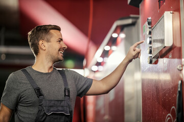 A happy worker is using car wash coin machine at car wash station.