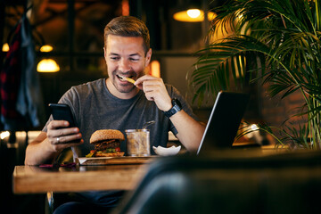 A casual entrepreneur is sitting on a lunch break and using cellphone at restaurant.