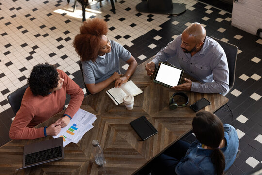 Overhead shot of a business team meeting looking at digital tablet