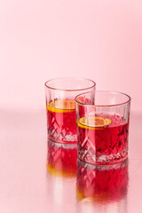 tropical red cocktails with lemon on pink background. minimal summer drinks vertical composition with copy space 