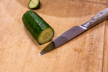 Abgeschnittene Gurke und ein Messer liegen auf einem Schneidebrett
