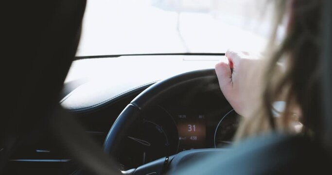 A woman confidently drives her car while keeping her hand firmly on the steering wheel - 31 km per hour 