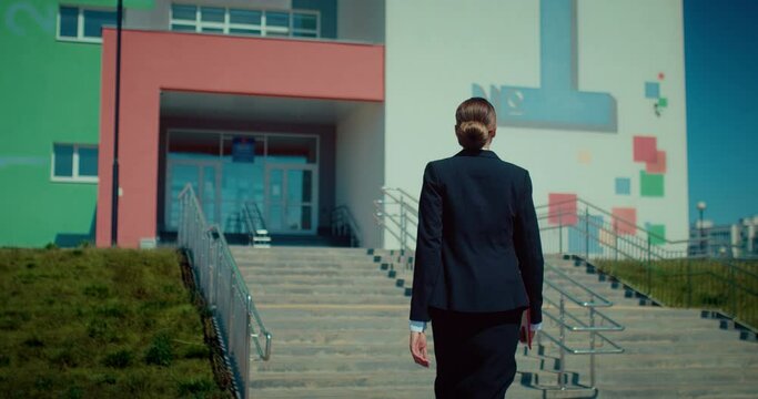 Female teacher going to school, back view, following shot of lady in classical suit, 4K, Prores
