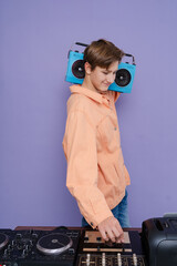 Charming boy hold boom box on his shoulder want listen  music isolated over bright color background