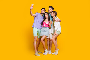 Full length photo of four people best friends have fun make selfie on smart cell device isolated bright color background