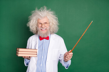 Photo of old professor with messy funky hair hold wooden pointer and books university isolated on green color background
