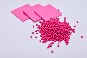 pink masterbatch granules with color chips as an example of the color produced, this polymer is a colorant for products in the plastics industry, isolated on white background