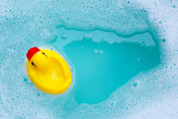 Yellow duck rubber toy with foam bubbles in blue basin