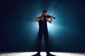 Plexiglas foto achterwand Intense violin recital with musician standing on stage with backlights against darkness with smoke. Concept of instrumental classic music festivals and concerts, art, culture. Ad © Lustre