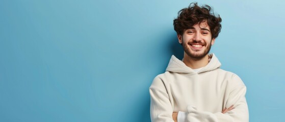 Portrait of happy man with curly hair smile toothily keeps arms down wears casual hoodie looks cheerful isolated over blue background being in good mood with copy space. Generative ai