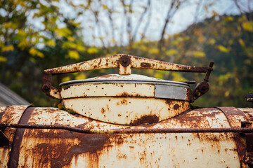 A rusty water tank close up. An iron very old and rusty white water tank in the garden, farm. Rust stains on white paint, old vintage rusty background