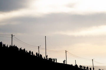 Silhouettes of people enjoying sunset from standing on a hill