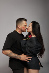 Kisses and hugs of couple in love, lovers. Passionate kisses on man face. Woman with rose flower in her husband hands