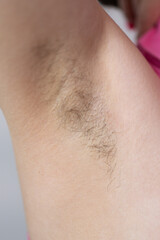 Close-up, woman showing hairy armpit in white tank top on white background, Concept: shaving...