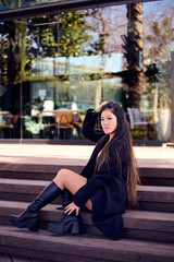 Fototapeta premium Portrait of a beautiful young Asian woman in a black coat and boots