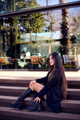 Fototapeta premium Portrait of a beautiful young Asian woman in a black coat and boots