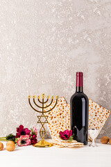 Vertical festive background for Jewish Passover holiday with traditional matzoth bread, red wine, flowers and golden minor candlestick. A copy space.