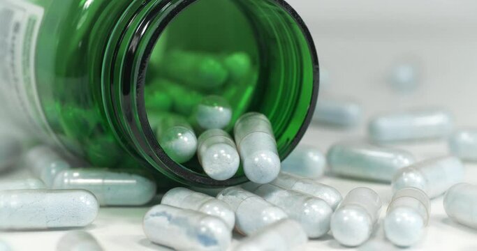 Capsules with blue powder scattered on the table. Open green container for nutritional supplements lies on the table. These are tablets of copper in chelated form