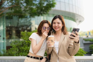 Happy asian colleagues browsing social media content during working day in outdoor office building using 5g wireless