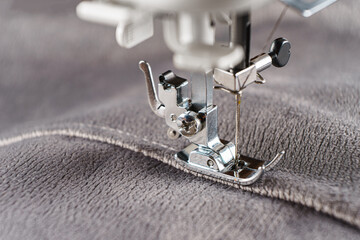 Modern sewing machine with gray velours fabric. Sewing process clothes, curtains upholstery....