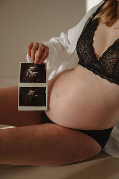 Young pregnant woman with ultrasound picture of baby, closeup