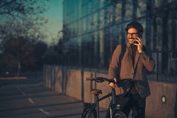 A smiling businessman in a suit standing on a bicycle lane and talking on a mobile phone